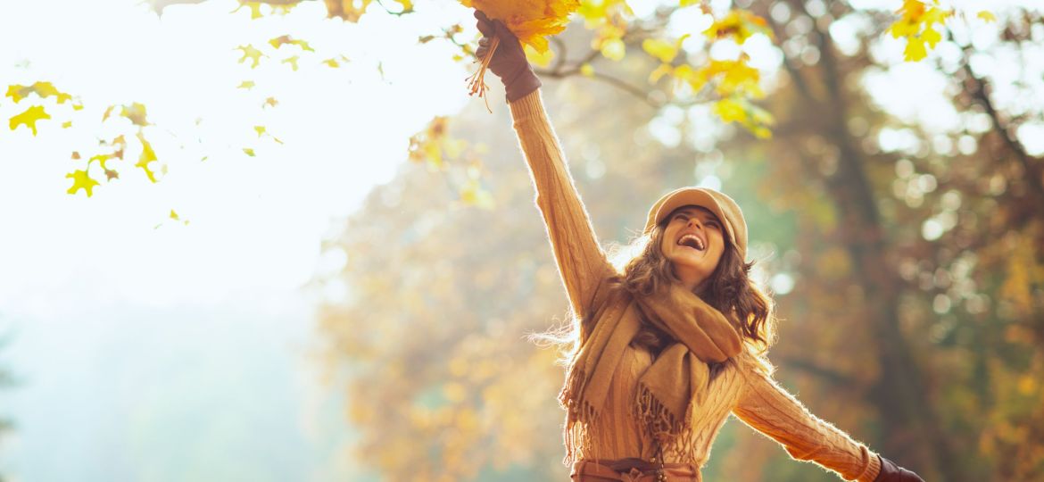 happy woman with yellow leaves rejoicing outside in autumn park